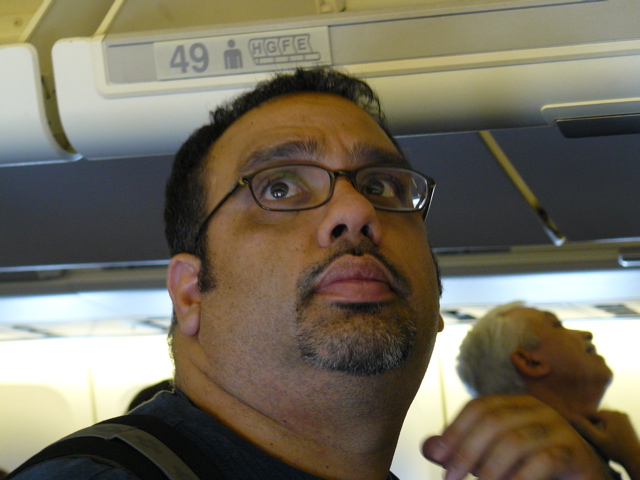 Karim is checking the overhead compartments before leaving the plane in Paris (rw)